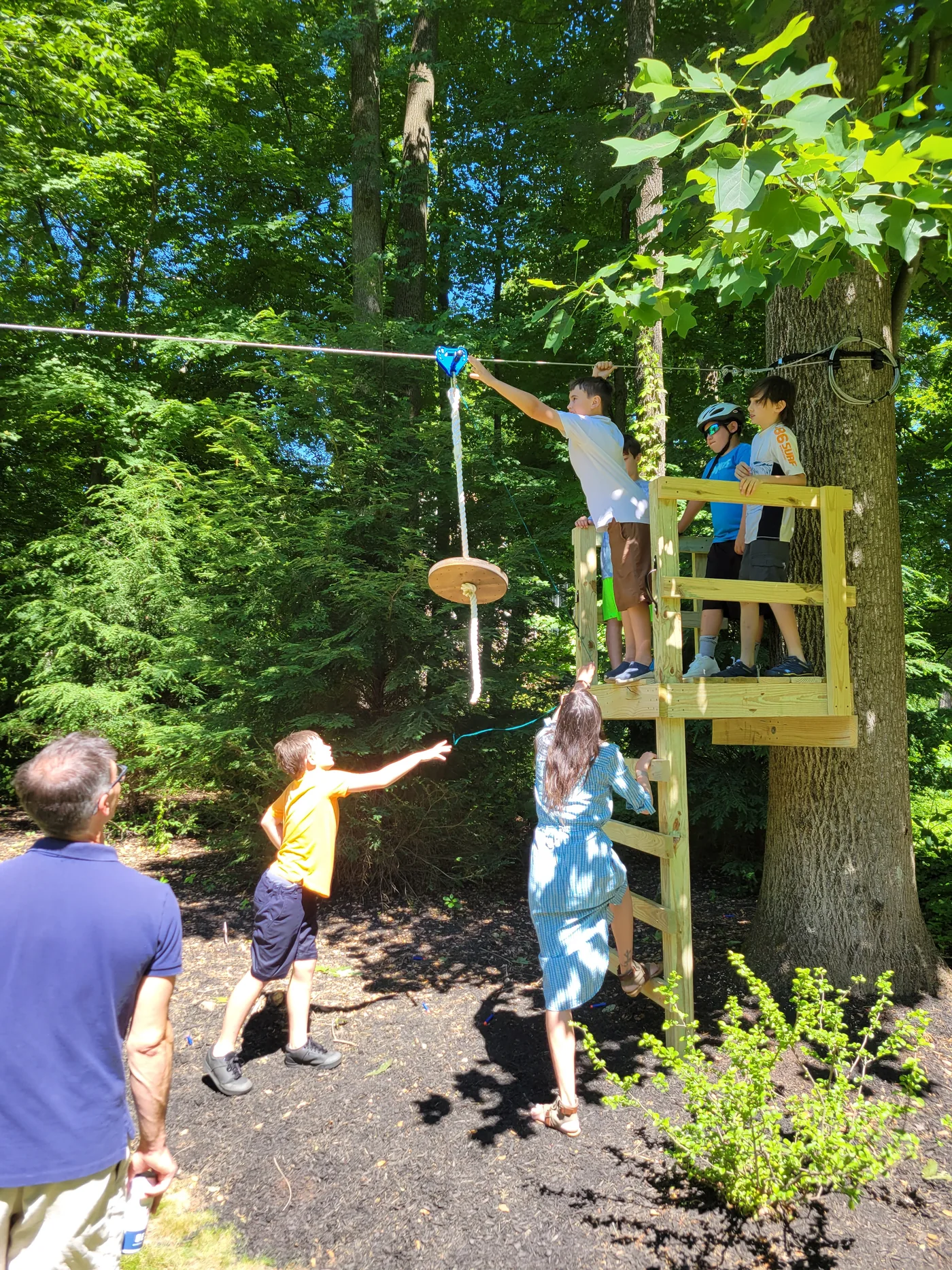 Children preparing to ride a backyard zip line from a wooden platform